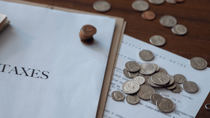 Stacked American coins beside a document labeled 'Taxes'.